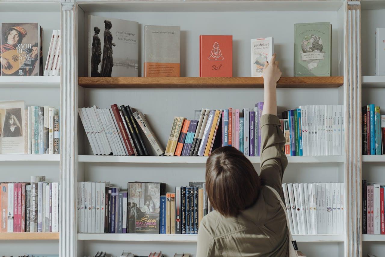 Человек выбирает книгу на полке